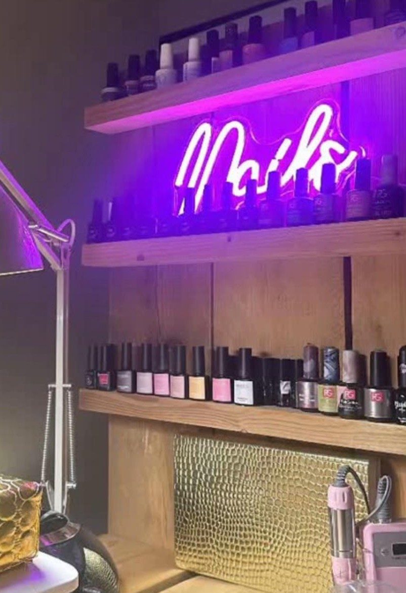 Planken vol gellak met een paars neonbord Nails