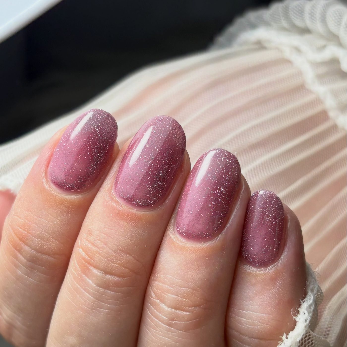 Mauve glitternagels, hand in een witte tule manchet